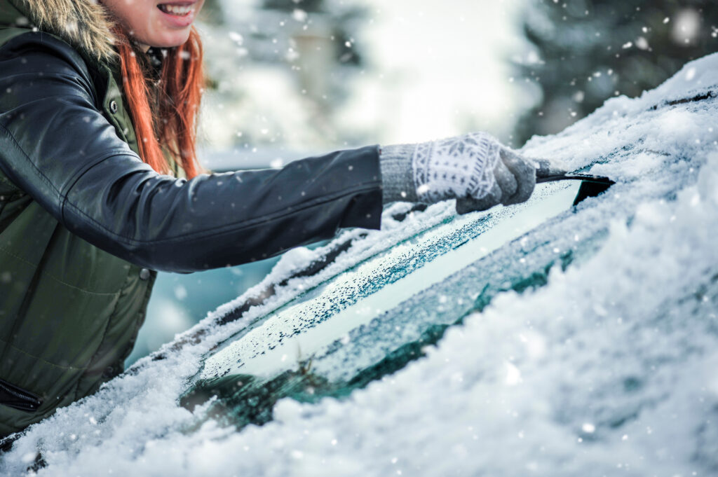 woman Removing snow from car windshield