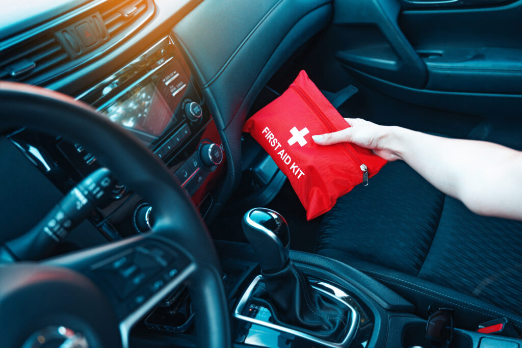 Female hand taking red first aid kit from the car glove box.